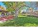 Backyard featuring green grass, mature trees, a deck, and bench seating at 3270 S Krameria St, Denver, CO 80222