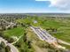 Aerial view shows parking, clubhouse, and golf course featuring ponds, trees, and lush green fairways at 7778 S Cherry Ct, Centennial, CO 80122