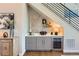 A modern bar with gray cabinets, a wine refrigerator, and stylish decor under the stairs at 10119 Bellwether Ln, Lone Tree, CO 80124