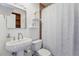 Bathroom featuring a pedestal sink, white toilet, and shower with white floral shower curtain at 7589 S Cove Cir, Centennial, CO 80122