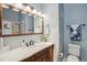Bathroom featuring a wood vanity, large mirror, and shower with decorative tile surround at 7589 S Cove Cir, Centennial, CO 80122