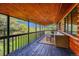 Covered deck boasts wood ceiling, log walls, views of nature, and comfortable seating, perfect for outdoor relaxation at 1353 S Elbert St, Elizabeth, CO 80107