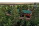 Exterior showing a log home nestled among mature trees with a metal roof, and outdoor pathways at 1353 S Elbert St, Elizabeth, CO 80107