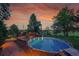 Backyard swimming pool features a slide, surrounding trees, and a sunset sky at 1353 S Elbert St, Elizabeth, CO 80107