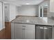 Bright kitchen with granite counters, white cabinets, and stainless steel dishwasher adjacent to living space at 3957 S Boston St, Denver, CO 80237