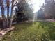 Lush backyard featuring a grassy lawn, mature trees, and a decorative rock border at 2488 W 111Th Pl, Denver, CO 80234