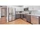 Updated kitchen showcases stainless steel appliances, tile backsplash, two-tone cabinets, and wood flooring at 2488 W 111Th Pl, Denver, CO 80234
