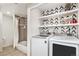 Convenient laundry area with modern washer and dryer, plus shelving for storage, adjacent to a tiled bathroom at 2488 W 111Th Pl, Denver, CO 80234
