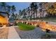 A serene backyard featuring a stone retaining wall, manicured lawn, rock garden, and patio with outdoor seating at 16244 Thunder Cat Way, Monument, CO 80132