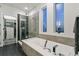 Luxurious bathroom featuring a soaking tub, walk-in shower, and stylish lighting fixtures with a view of a large closet at 16244 Thunder Cat Way, Monument, CO 80132