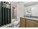 Modern bathroom featuring a tiled shower and bathtub with a dark shower curtain and wood vanity at 16244 Thunder Cat Way, Monument, CO 80132