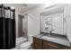 Modern bathroom featuring a tiled shower and bathtub with a dark shower curtain and wood vanity at 16244 Thunder Cat Way, Monument, CO 80132