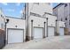 View of three private, attached garages in modern home development with concrete driveway and white exteriors at 1252 Yates St, Denver, CO 80204