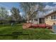 Backyard with lawn, brick deck, large tree and playground equipment visible behind a fenced yard at 6705 Nelson St, Arvada, CO 80004