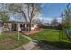 Backyard featuring a brick deck, lawn, and large tree providing shade, with house view at 6705 Nelson St, Arvada, CO 80004
