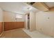 Unfinished basement area featuring carpet, wood paneling, patterned wallpaper, window, and closet at 6705 Nelson St, Arvada, CO 80004