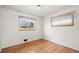 Simple bedroom with hardwood floors, white walls, and natural light from two windows at 6705 Nelson St, Arvada, CO 80004