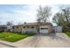 Ranch-style home with a brick facade, covered porch, attached garage, and paved driveway at 6705 Nelson St, Arvada, CO 80004