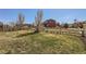 Spacious backyard with mature trees, a grass lawn and a wooden fence surrounding the property at 1421 Rustic Dr, Longmont, CO 80504