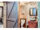 Unique bathroom featuring wood-paneled walls, a vibrant sink, and a sliding barn door at 1421 Rustic Dr, Longmont, CO 80504