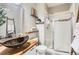 Bathroom showcasing modern vessel sink, decorative shelves and walk-in shower with glass enclosure at 1421 Rustic Dr, Longmont, CO 80504