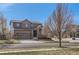 Beautiful two-story home featuring a two-car garage, stone accents, and mature trees on a sunny day at 1421 Rustic Dr, Longmont, CO 80504