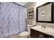 Cozy bathroom featuring patterned shower curtain, vanity with sink, mirror, and open shelving for storage at 5519 Tucson St, Denver, CO 80239
