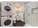 Modern bathroom with black and white tile, glass shower, and stackable washer and dryer at 2555 Hudson St, Denver, CO 80207