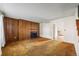 Spacious living room featuring wood paneling, a fireplace, and neutral carpet at 4445 S Lowell Blvd, Denver, CO 80236