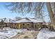 Brick Ranch home with yellow door, snowy yard, and mature trees at 543 S Bryant St, Denver, CO 80219