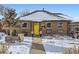 Brick Ranch home with yellow door and snowy front yard at 543 S Bryant St, Denver, CO 80219