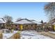 Brick Ranch home with yellow door, snowy yard, and mature trees at 543 S Bryant St, Denver, CO 80219