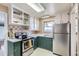 Updated kitchen with green cabinets, stainless steel appliances, and tiled backsplash at 543 S Bryant St, Denver, CO 80219