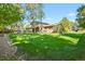 Expansive backyard showcasing a lush lawn, mature trees, and the home's exterior with a covered patio at 455 Greenwood, Longmont, CO 80504