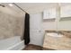 Full bath featuring a vanity with dark cabinets, tiled walls, and a shower-tub combo with a curtain at 47341 Lily Ave, Bennett, CO 80102