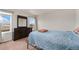 Cozy bedroom featuring a large dresser with mirror and a comfortable bed with a blue patterned cover at 47341 Lily Ave, Bennett, CO 80102