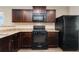 Modern kitchen featuring dark wood cabinets, black appliances, and durable countertops at 47341 Lily Ave, Bennett, CO 80102