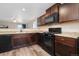 Well-equipped kitchen with dark wood cabinets, black appliances, and a practical layout at 47341 Lily Ave, Bennett, CO 80102