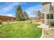 A spacious backyard with a lush lawn, patio seating, a wooden fence, and mature trees at 6769 W 70Th Ave, Arvada, CO 80003