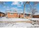 Brick ranch house with a snow-covered front yard and large trees at 3345 W Aqueduct Ave, Littleton, CO 80123