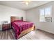 Bedroom with laminate floors, ceiling fan, window AC unit, and a red plaid bedspread at 2829 W College Ave, Denver, CO 80219