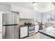 Functional kitchen with white cabinetry, stainless steel refrigerator, and tiled countertops and backsplash at 2829 W College Ave, Denver, CO 80219