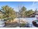 Tranquil backyard view featuring a small creek bed, mature evergreens, and a charming wrought-iron fence at 12 Canon Cir, Greenwood Village, CO 80111