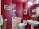 A cozy bathroom with a pedestal sink, toilet, and unique round mirror against a red wall, creating a warm and inviting space at 12 Canon Cir, Greenwood Village, CO 80111