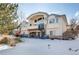 Elegant home exterior showcasing a spiral staircase, stone accents, and a fenced yard covered in snow at 12 Canon Cir, Greenwood Village, CO 80111