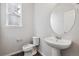 Half bath featuring a pedestal sink, oval mirror, and window at 1349 Brookfield Pl, Erie, CO 80026