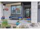 A cozy front porch with hanging flower baskets, potted plants, and bench seating with blue cushions at 16486 W 94Th Dr, Arvada, CO 80007