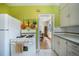 Retro kitchen featuring lime green walls, white appliances and cabinets, and colorful hanging cookware at 45 S Grove St, Denver, CO 80219