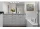 Elegant bathroom featuring double sinks, sleek white cabinetry, and a luxurious soaking tub for ultimate relaxation at 7746 E Severn Pl, Denver, CO 80230