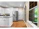 Bright kitchen featuring white cabinets, stainless steel refrigerator, and a view of the outdoors at 7746 E Severn Pl, Denver, CO 80230
